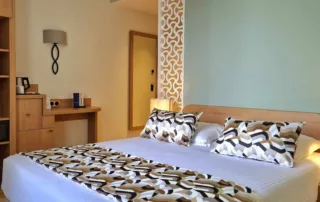 Chambre double spacieuse avec lit double, cloison décorative et ambiance méditerranéenne.