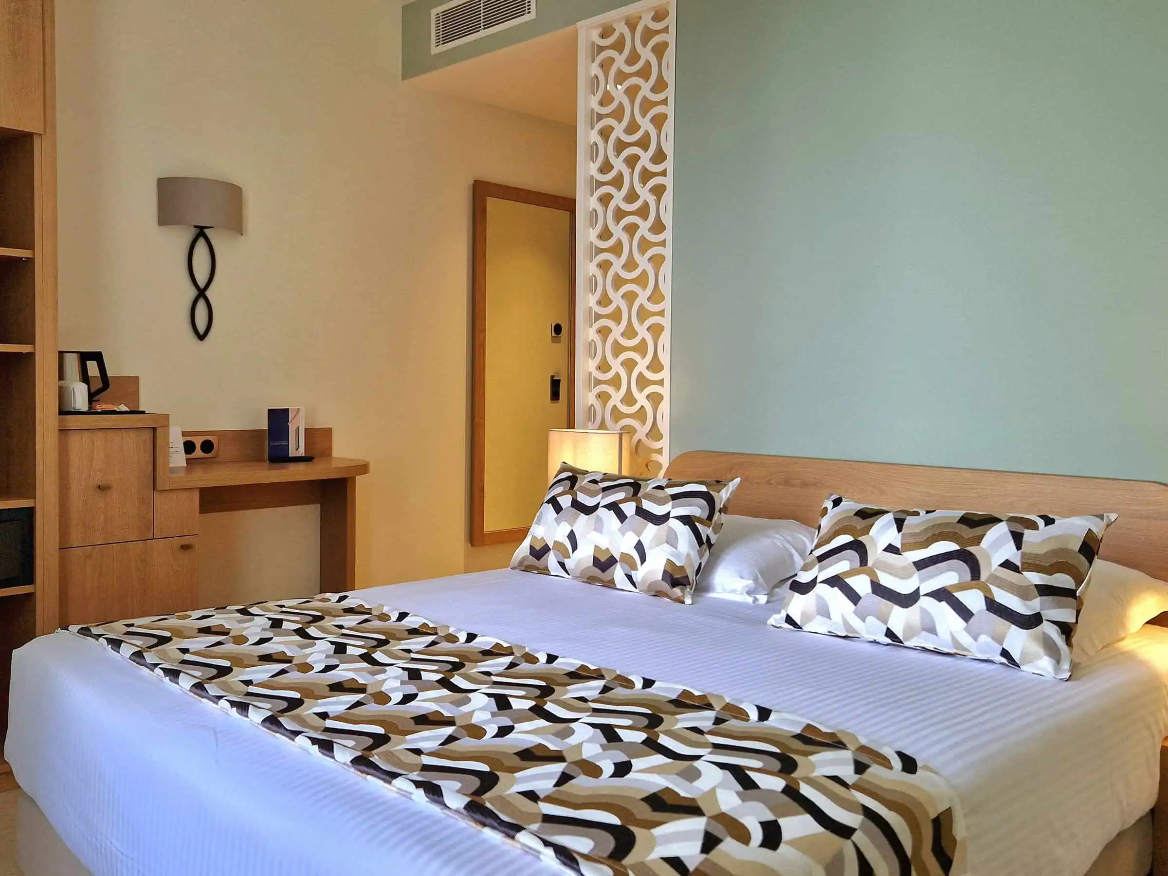 Chambre double spacieuse avec lit double, cloison décorative et ambiance méditerranéenne.